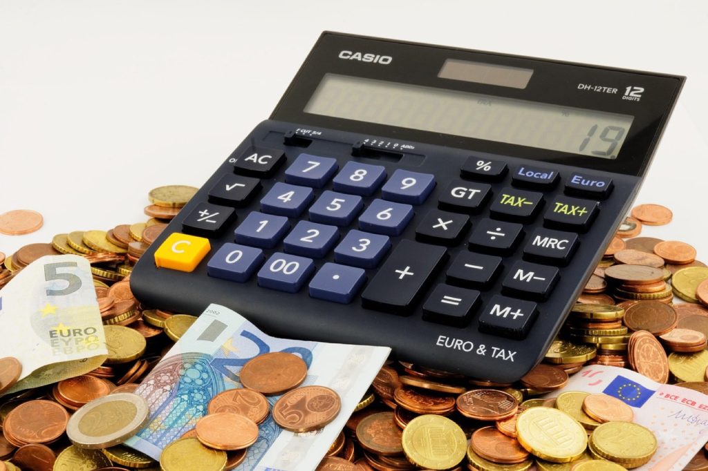A desktop calculator resting on a spread of banknotes and coins
