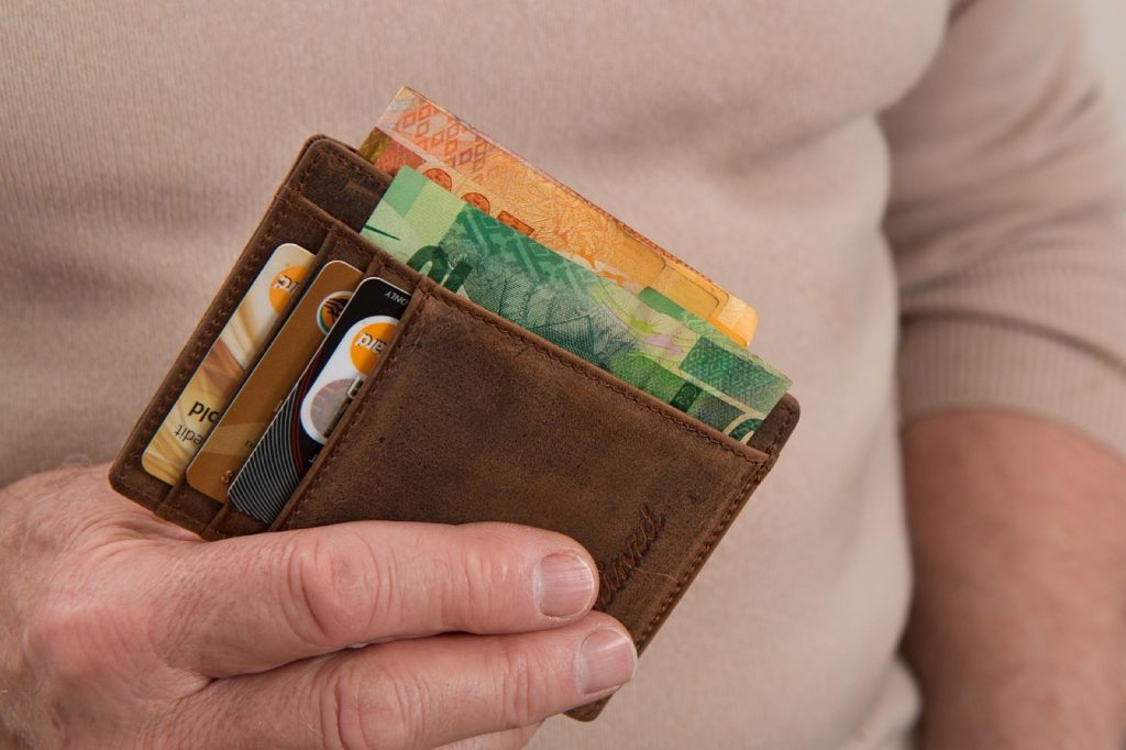 A person holding an open wallet with cards and cash