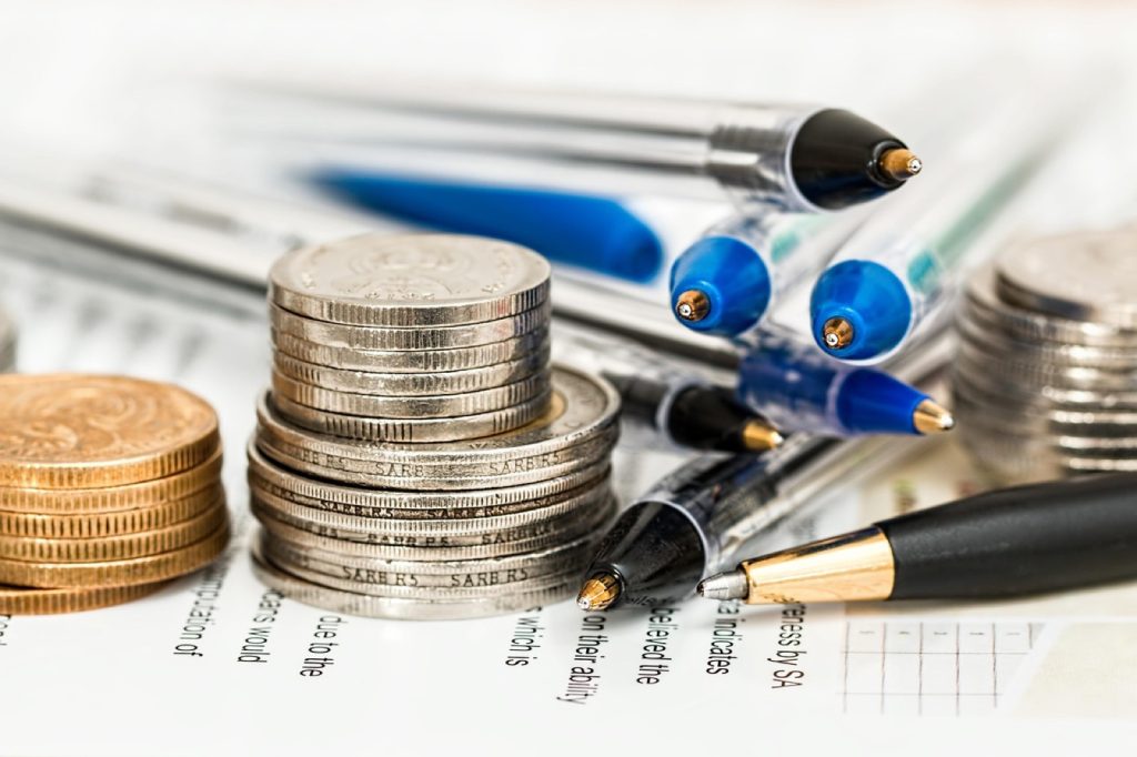 Stacks of coins and pens resting on a printed spreadsheet