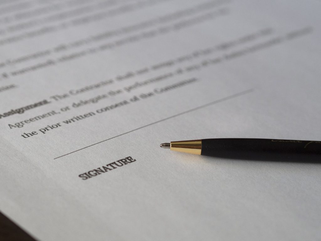 A pen resting on the signature line of a printed contract