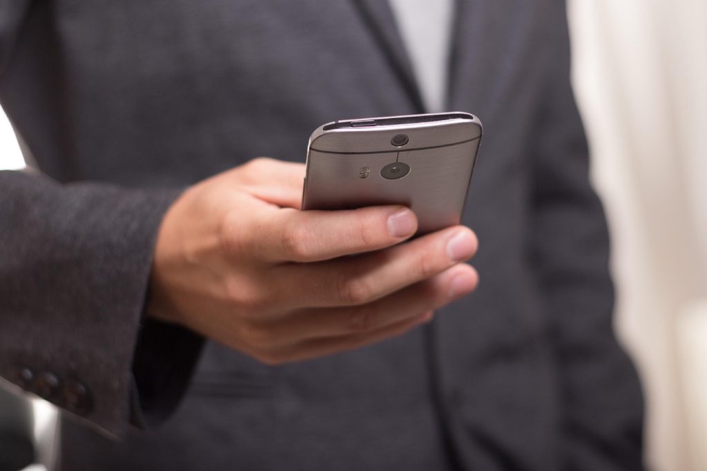A person in a suit holding a smartphone, mid-call