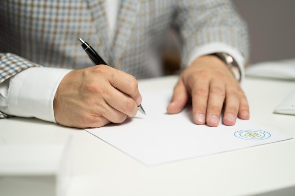 A person signing a loan agreement with a pen.