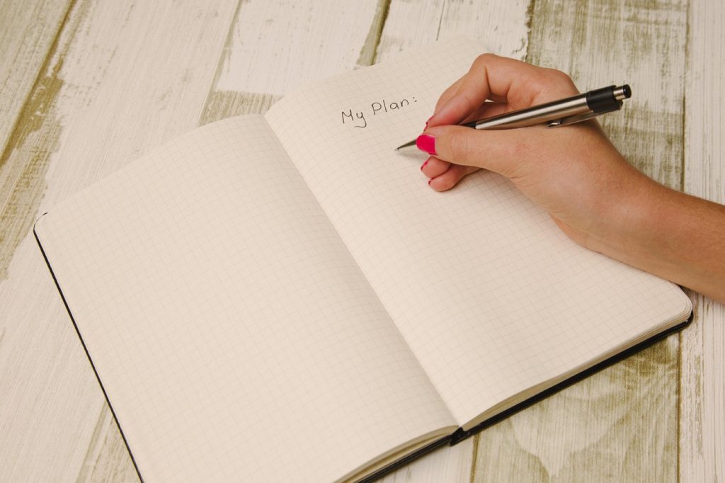 Writing a monthly plan in a paper planner.